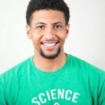 Home Portrait of a smiling young man wearing a green T-shirt with science text.